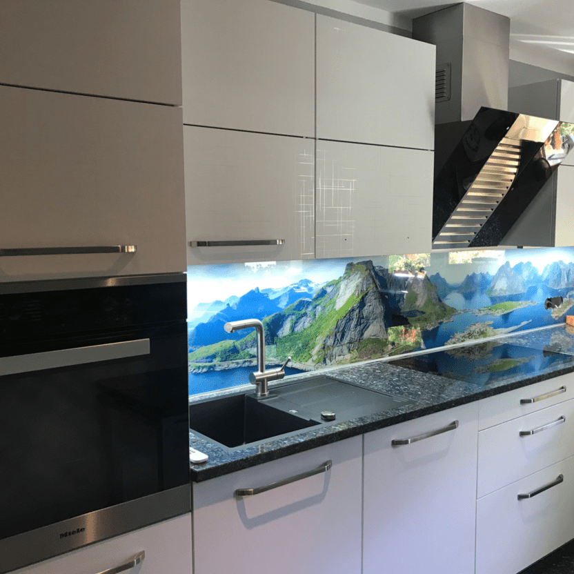 Küche nach Maß mit Fotoglasrückwand im Gebirgsmotiv und glänzenden weißen Fronten.