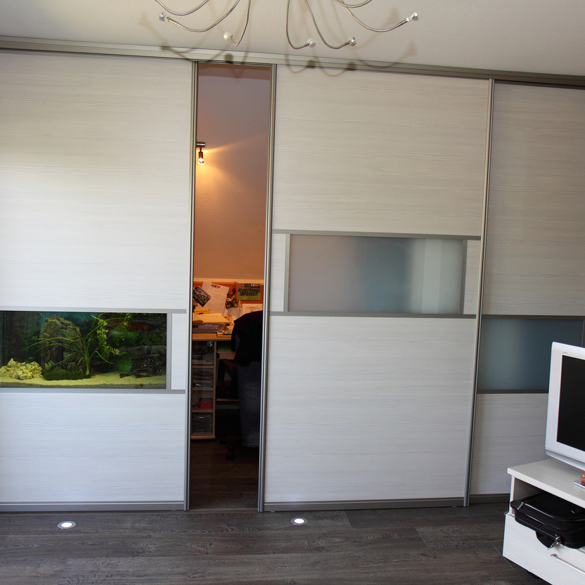 Heller Raum mit modernen Schiebetüren, integriertem Aquarium und Milchglasfeldern als dekorativem Raumteiler.
