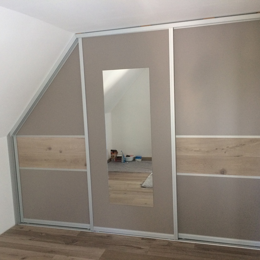 Maßgefertigter Schiebetürenschrank unter Dachschräge mit Spiegelfront und Holzdekor in modernem Schlafzimmer.
