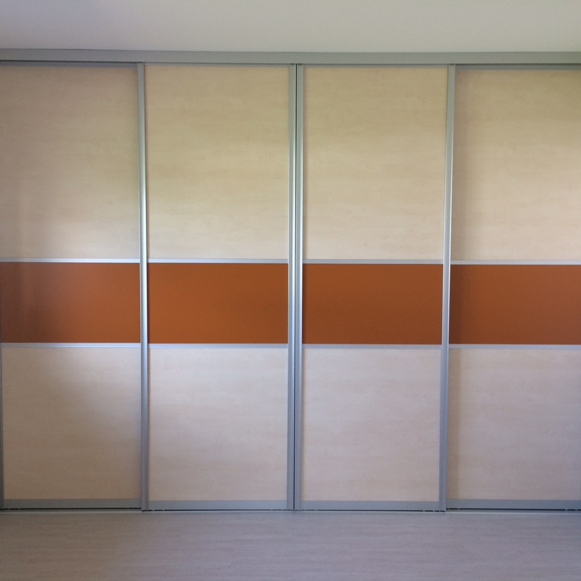 Heller Schiebetürenschrank mit cremefarbenen Flächen und orangen Mittelstreifen in modernem Schlafzimmer mit Holzfußboden.