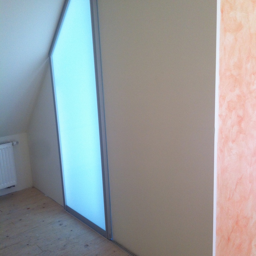 Schiebetür aus Milchglas unter Dachschräge, mit abgeschrägtem Glaselement und hellem Holzfußboden.