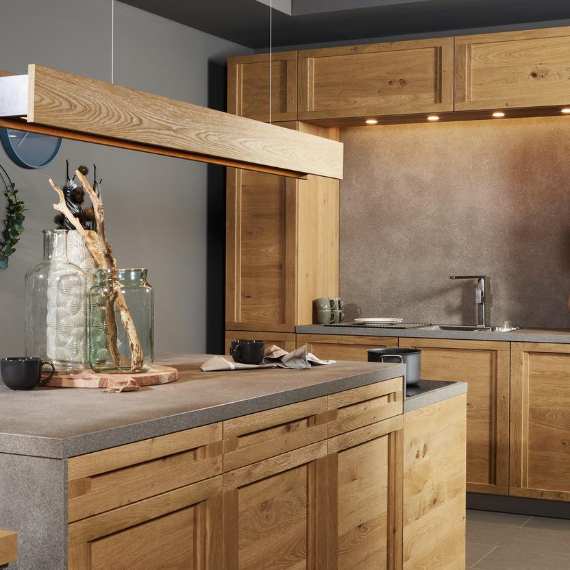 Küche nach Maß mit Holzfronten, grauer Arbeitsplatte und stimmungsvoller Nischenbeleuchtung.