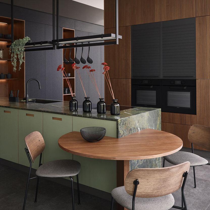 Küche nach Maß mit grünem Naturstein, Holzpaneelen und rundem Esstisch im Loft-Stil.